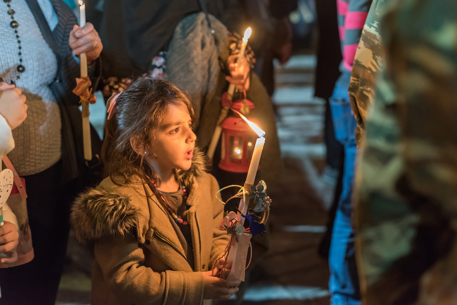 young girl holding a lit candle during Greek Orthodox Easter 
